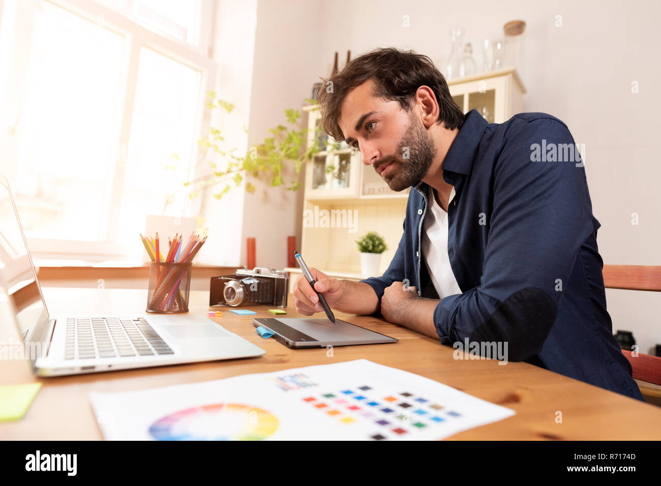 Graphic designer che lavora sulla tavoletta digitale. Libero professionista a lavorare a casa. Foto Stock