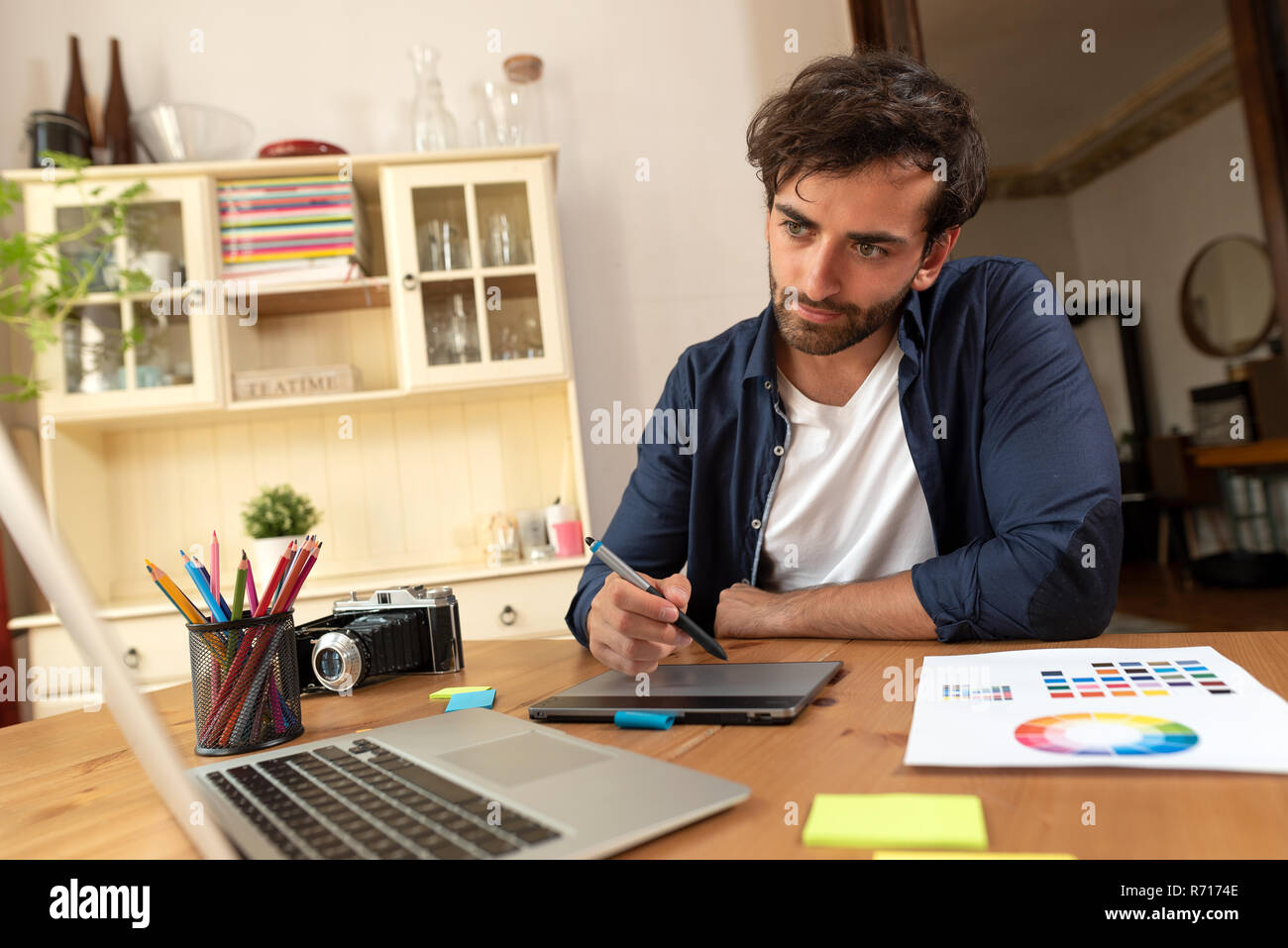 Graphic designer che lavora sulla tavoletta digitale. Libero professionista a lavorare a casa. Foto Stock