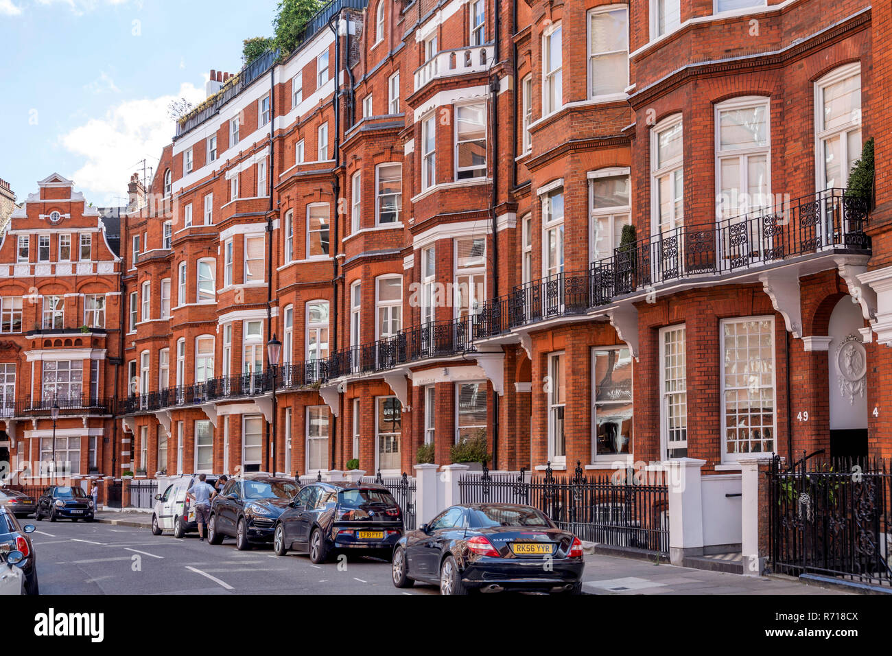 Fila di case con edificio in mattoni rossi in stile vittoriano, nel quartiere di Kensington, London, Regno Unito Foto Stock