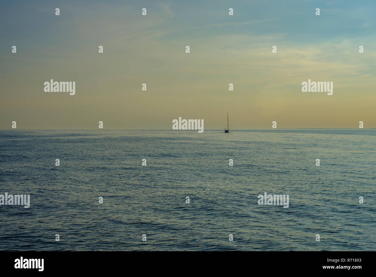 Una barca a vela sul aprire l'acqua nella luce della sera. Foto Stock