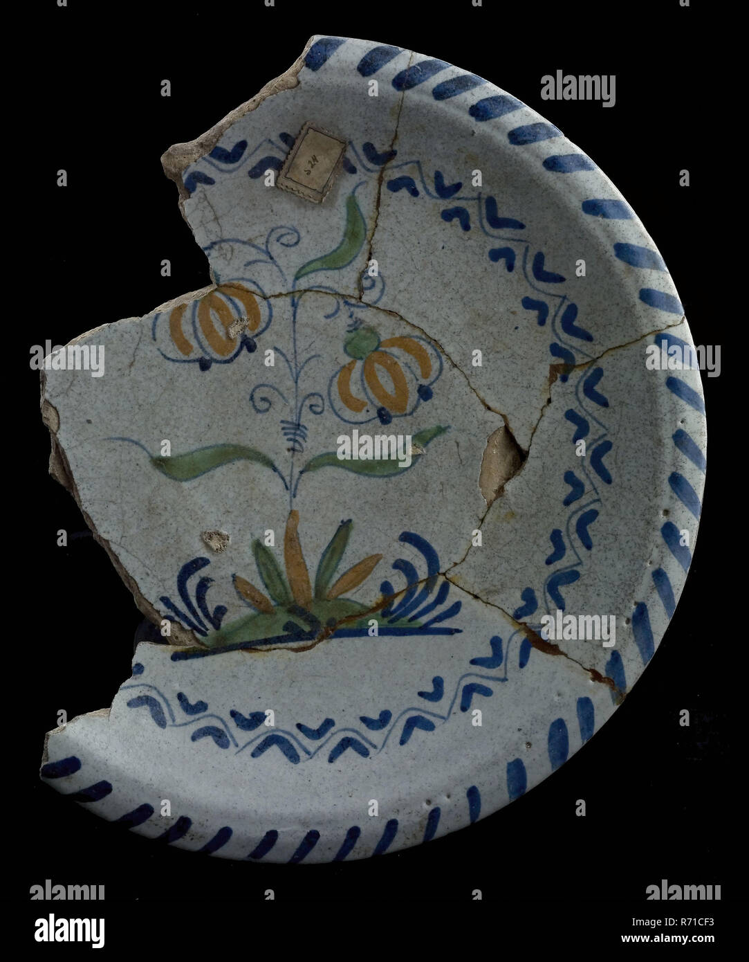 Frammento di piatto in maiolica policroma,, i tulipani sul suolo, cavo edge, piastra di supporto delle stoviglie suolo trovare ceramica smalto di terracotta, cotta sotto coperta con smalto piombo globs verde e color rame delle candelette di archeologia policromi decorano Rotterdam cibo tulip varietà Bottomvondst Rotterdam 1941. Foto Stock