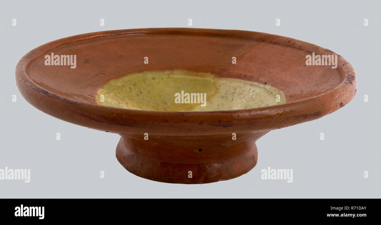 Sale di terracotta ciotola, rosso di Shard, con giallo all'interno, sale-piatto porta-stoviglie in ceramica di terracotta smalto di terracotta, girate a mano smaltato cotto sale di terracotta piatto. Red shard interamente vetrato. A forma di ciotola specchio con bandiera angolata tratto profondo giallo satinato. Standring. Restauro è ridipinto di archeologia città di Rotterdam Oostplein triangolo fossa sotterranea indigeni sale di terracotta tabella che serve cibo condimento scoperta del suolo Rotterdam fossa sotterranea Oostplein dal grande fossa per la spazzatura 1976. Foto Stock