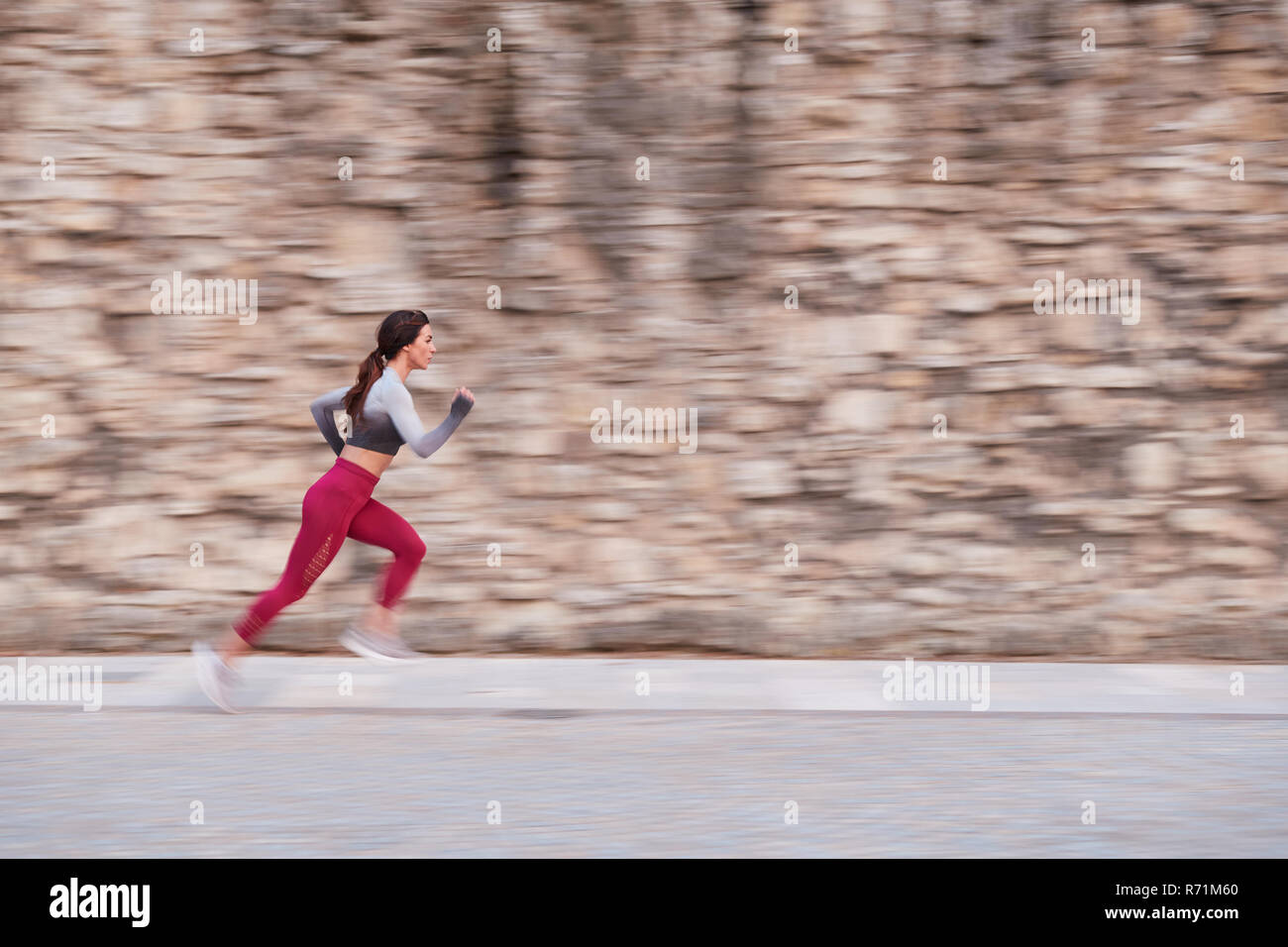 Una singola femmina jogging in una città urbana, posizione durante il tramonto Foto Stock