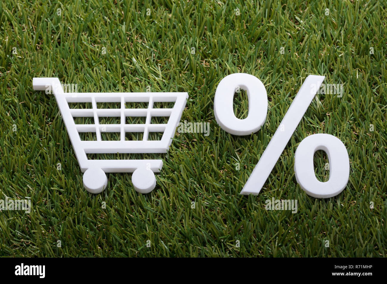 Miniatura Shopping Cart e segno di percentuale su erba verde Foto Stock