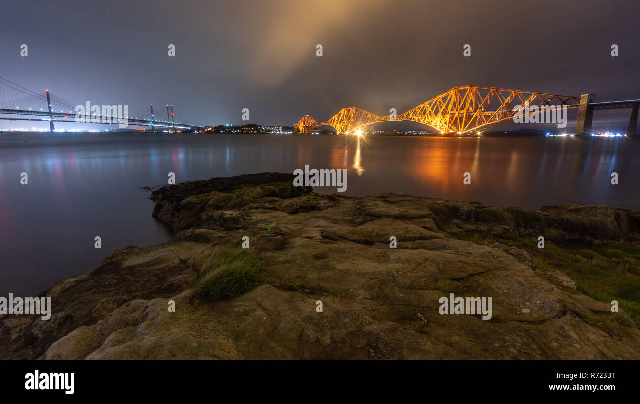 Il Forth Bridge è illuminata al tramonto del Firth of Forth a South Queensferry a Edimburgo, Scozia. Foto Stock