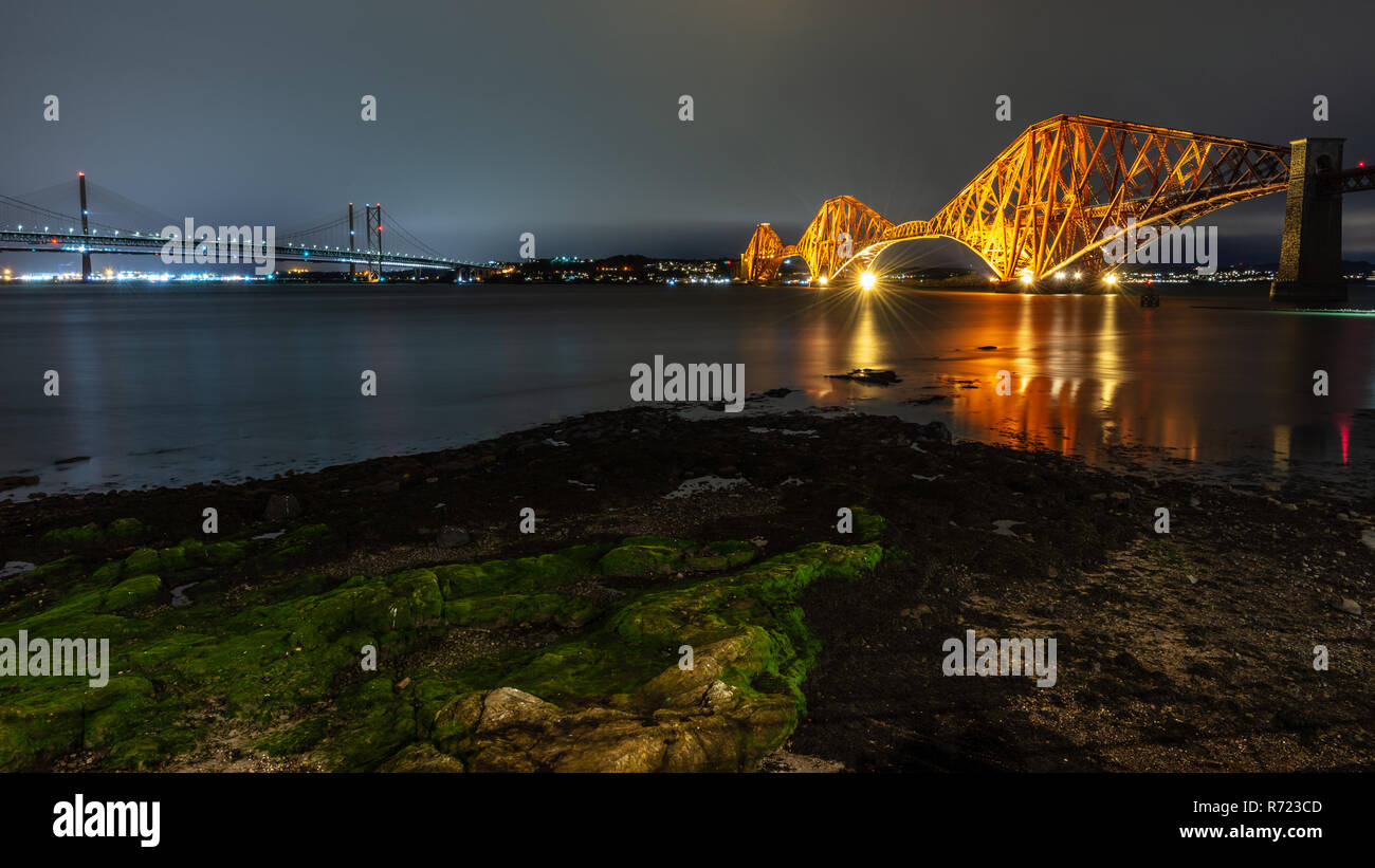 Il Forth Bridge è illuminata al tramonto del Firth of Forth a South Queensferry a Edimburgo, Scozia. Foto Stock