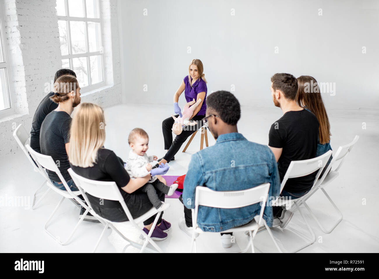 Gruppo di persone durante il corso di formazione con istruttore che mostra sul manichino bambino come fornire il primo soccorso per la soffocante bambino Foto Stock