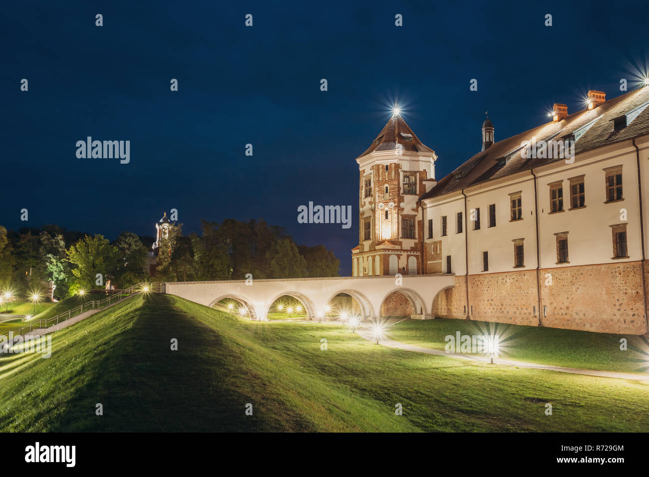 Mir, Bielorussia. Complesso del Castello di Mir in serata luci di illuminazione. Famoso punto di riferimento, antico monumento gotico del feudalesimo sotto la notte blu cielo. UNESCO Foto Stock