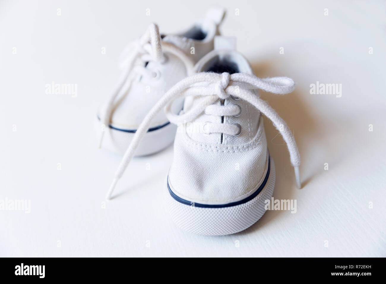 White baby sneakers. Le prestazioni di maternità e di concetto del neonato Foto Stock