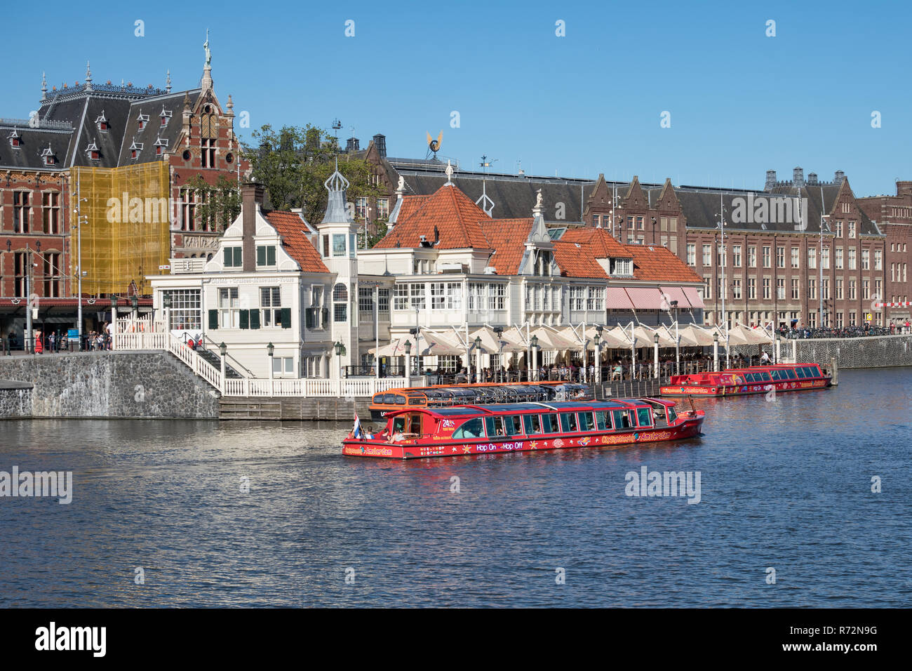 Canali di Amsterdam con lancia e edifici vicino stazione ferroviaria centrale Foto Stock