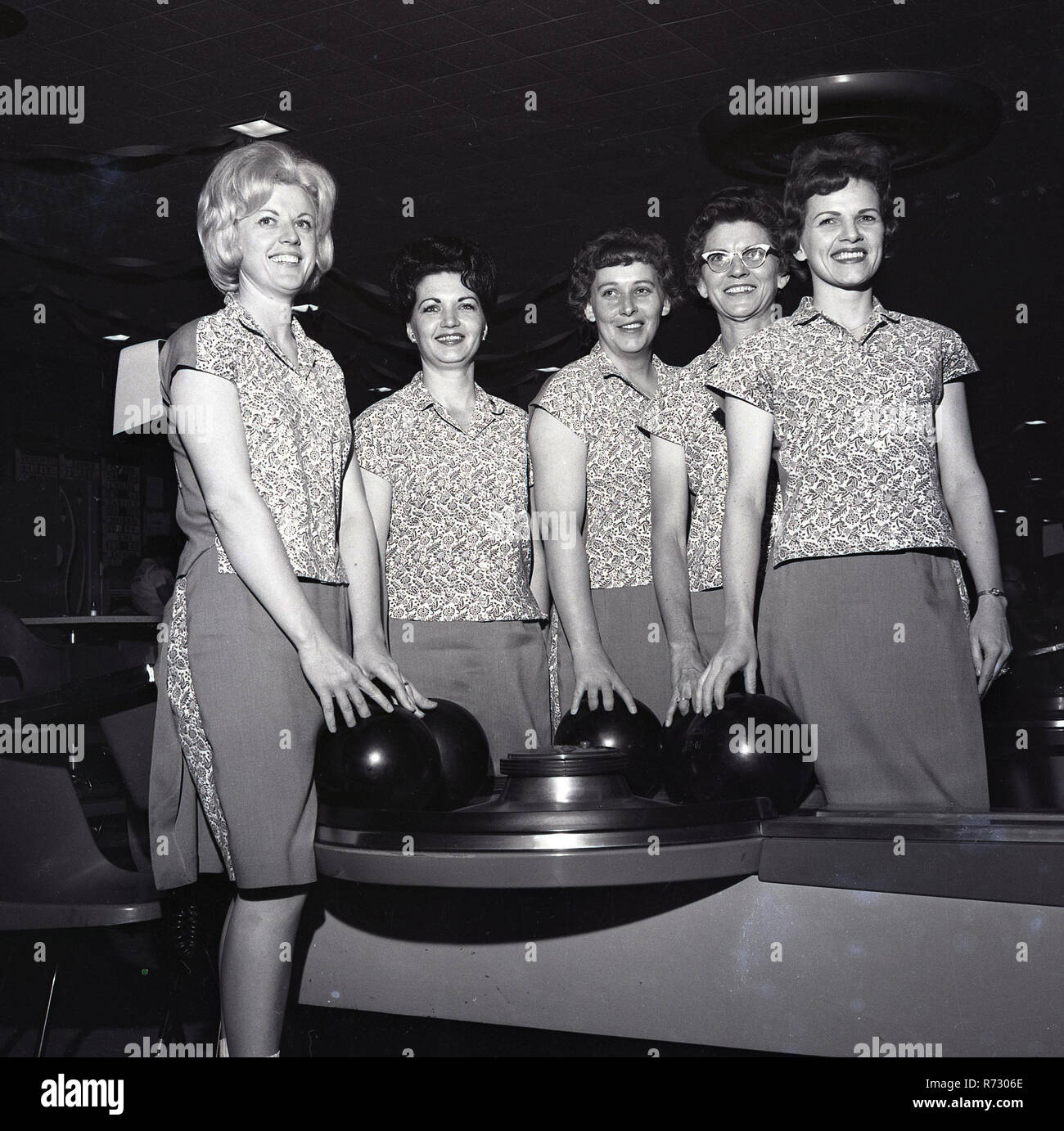 1964, storico, un signore ten-pin bowling team indossando il loro kit squadra di cime e gonne in piedi insieme mediante la macchina di bowling, STATI UNITI D'AMERICA. Negli anni sessanta, ten-pin bowling è stato un popolare sport e attività ricreative e ha visto un boom con oltre 12.000 vicoli costruito. Foto Stock