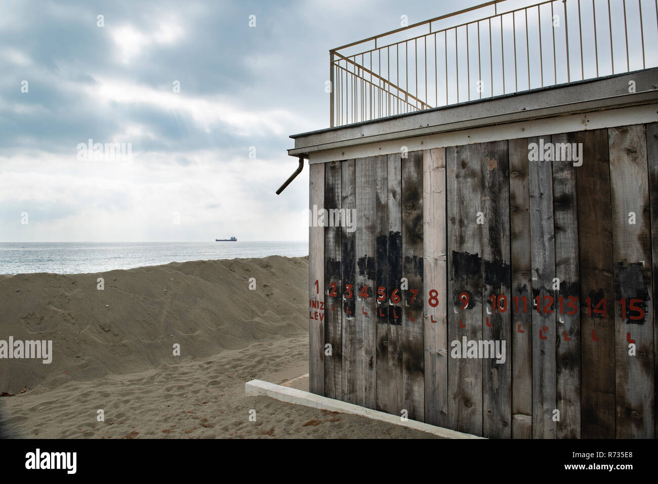 Facciate ricoperte con tavole di legno per proteggere contro il maltempo invernale e le tempeste del mare, di fronte alla costruzione di una duna di sabbia sul fondo un olio Foto Stock