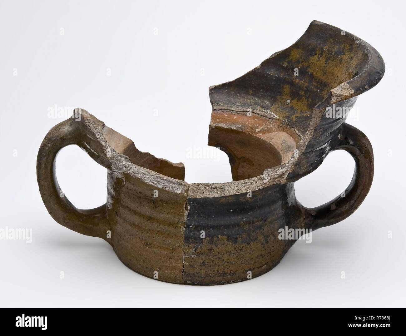 Frammento di stufa di maiolica o macchia di terracotta rossa, modello di mortaio, lo sfregamento frammento del riscaldatore in ceramica di terracotta terraglia smalto smalto di piombo, girato a mano impostare trafitto cotto smaltato in terracotta rossa marrone giallo smalto all'interno parzialmente con macchie nere due orecchie foro nella parete rotazioni. Stufa o braciere in forma di mortaio archeologia Valckensteyn Poortugaal Albrandswaard indigeni cucina in ceramica Stufe di cottura riscaldamento carburante scoppiettante fuoco scoperta del suolo: canal al castello di cucina Valckensteyn a Poortugaal ora Albrandswaard 1961 Foto Stock