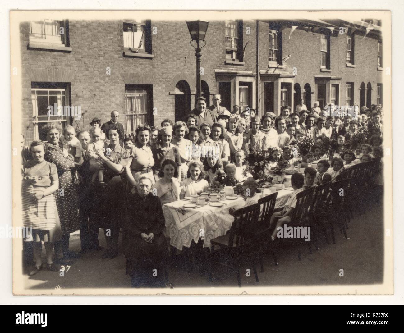 Cartolina originale dell'era WW2 del giorno della V.E. della cartolina / Festa del tè in Europa, 9 maggio 1945. Si tennero feste per celebrare la fine della seconda guerra mondiale in Europa, luogo sconosciuto in una strada britannica. Tipiche celebrazioni per il V.E. Day. Ricordi di guerra. Regno Unito datato 12 maggio 1945. Foto Stock