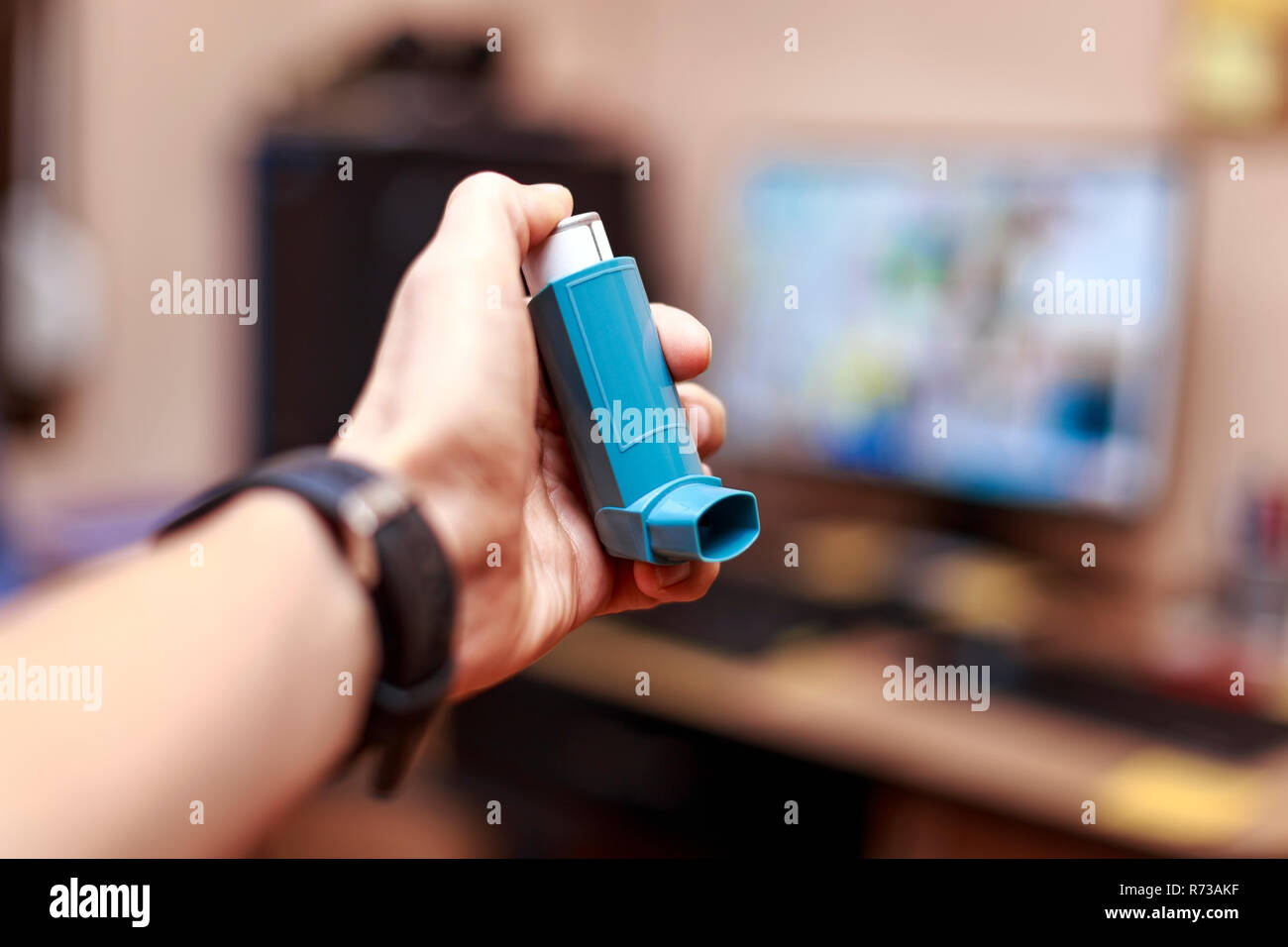 Uomo caucasico con asma spray in mano all'ufficio. Attacco d'asma la birou concetto. Foto Stock