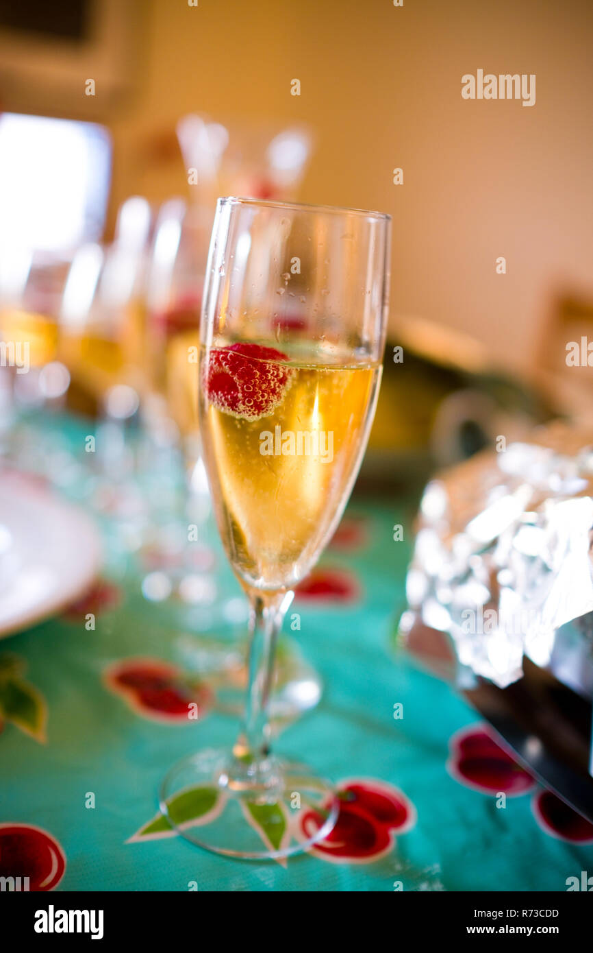 Chiudere atmosferica di bicchieri di champagne con champagne e lamponi flottante con le bolle in vetri scanalati su una tavola durante il giorno del ringraziamento Foto Stock