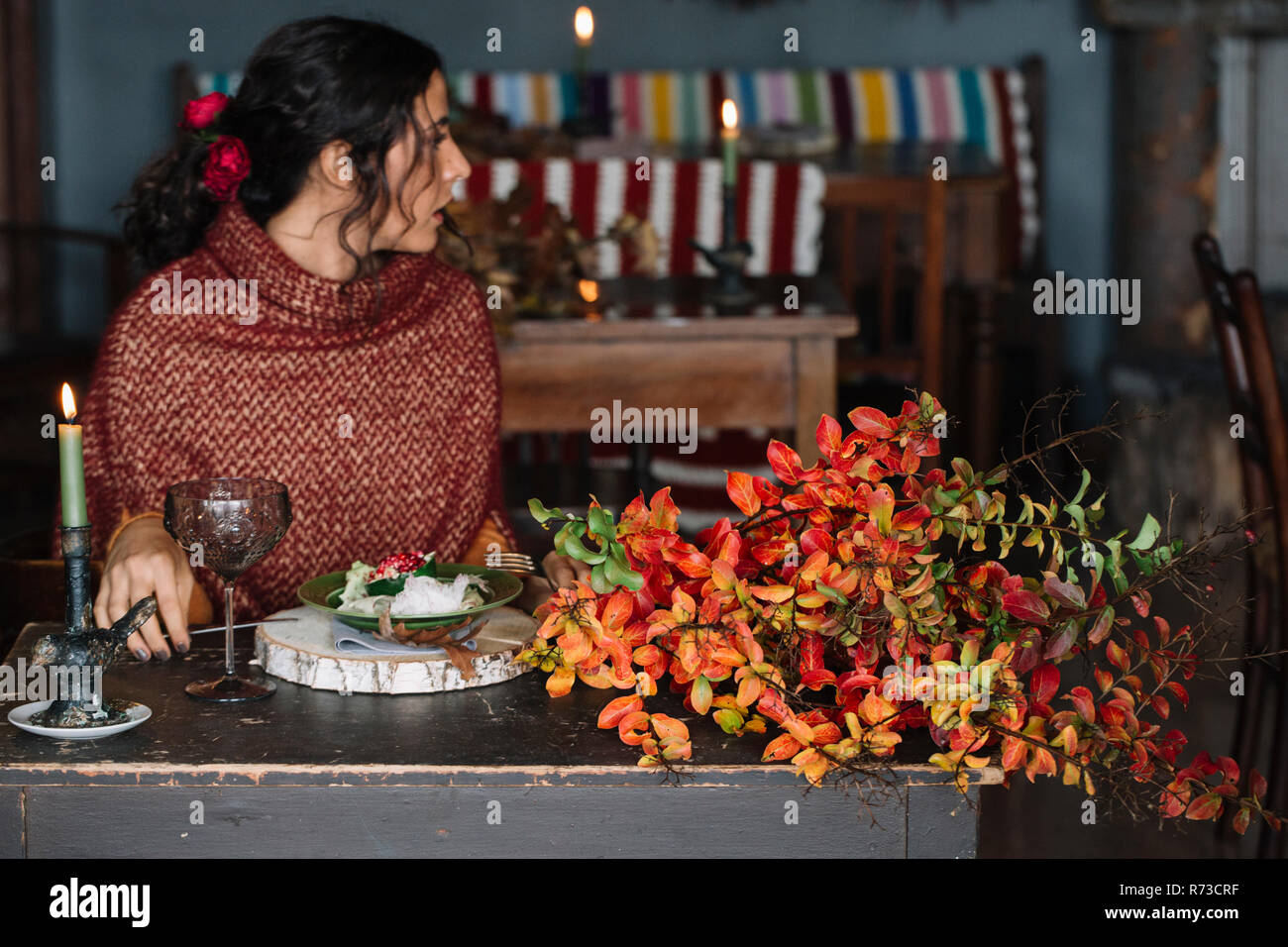 Giovane donna guardando sopra la sua spalla da tavolo per la cena Foto Stock
