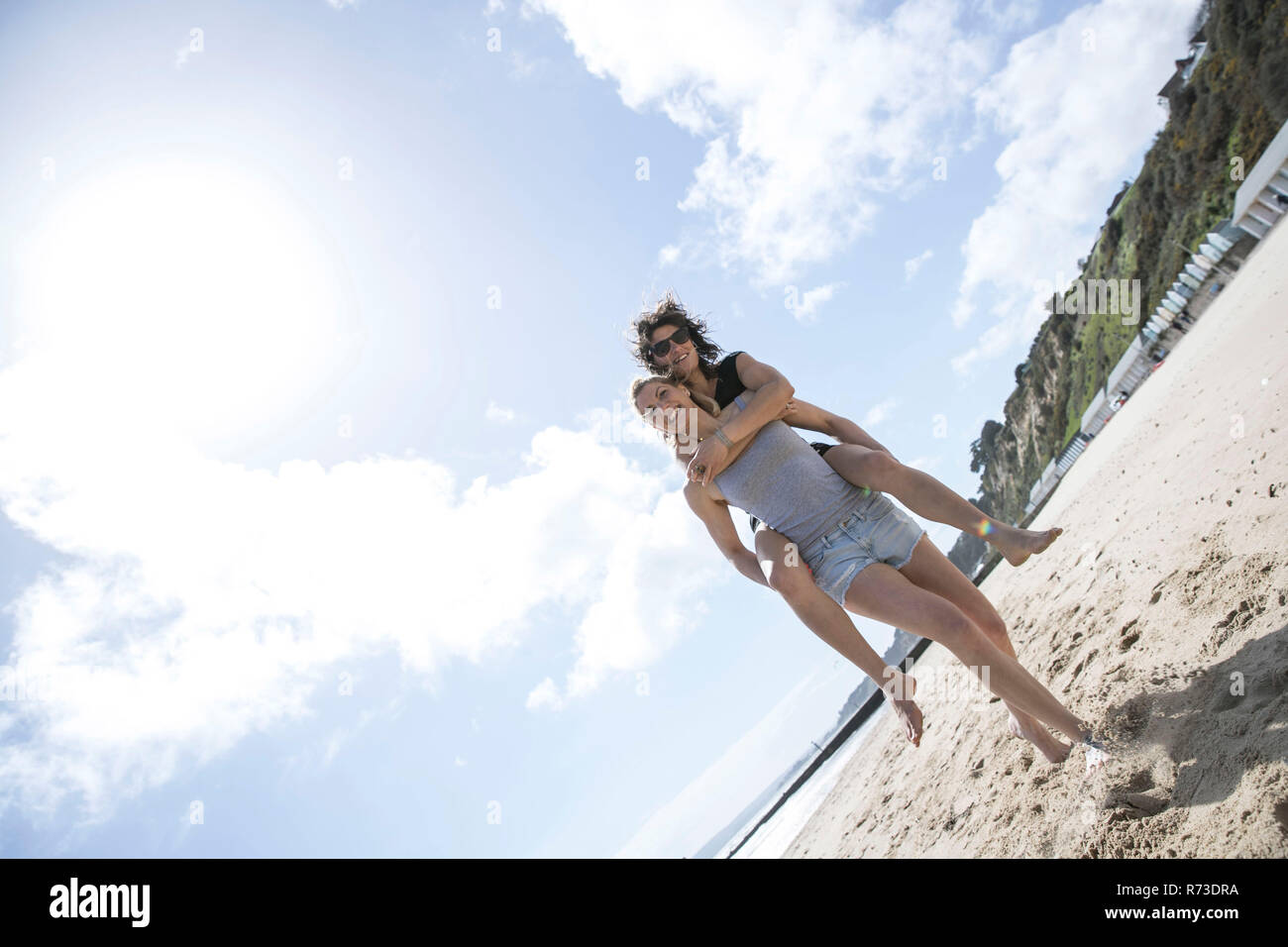 Sorelle giocando piggyback sulla spiaggia, Bournemouth, Regno Unito Foto Stock