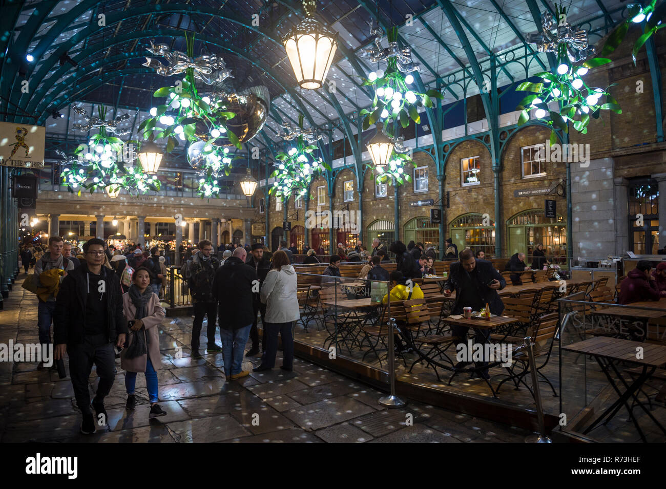 Londra - 26 novembre 2018: i turisti passeggiare sotto grandi decorazioni di Natale Illuminazione del colonnato est di Covent Garden. Foto Stock
