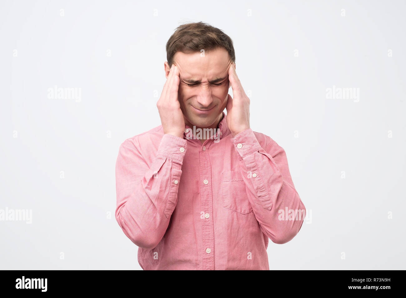 Bel uomo europeo che mostra quanto il suo mal di testa, dolore, cercando esaurito Foto Stock