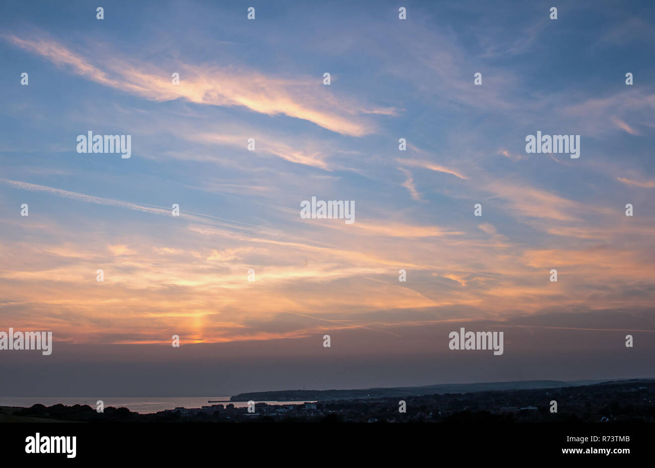Tramonto e sun pilastro su Seaford Bay, Sussex. Foto Stock