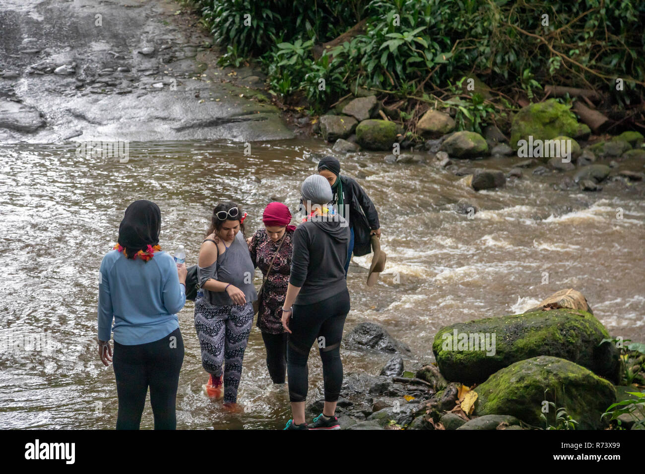 Le persone attraversano un fiume durante un acquazzone in Waipi"o valle sulla Big Island delle Hawaii. Foto Stock