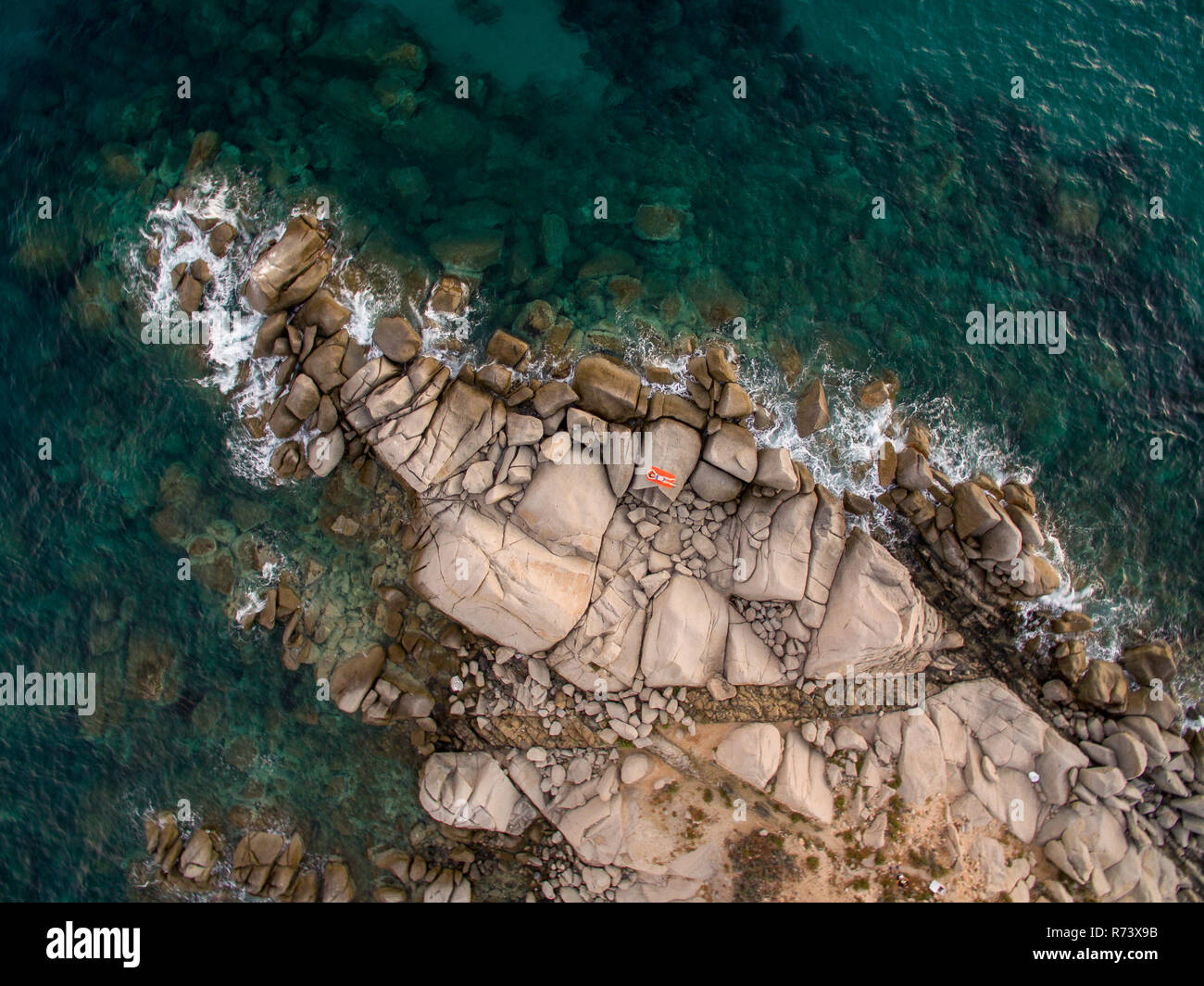 Fotografia aerea della sardegna costa durante un tramonto d'estate. Piccole onde sulle rocce prese con un drone. Foto Stock
