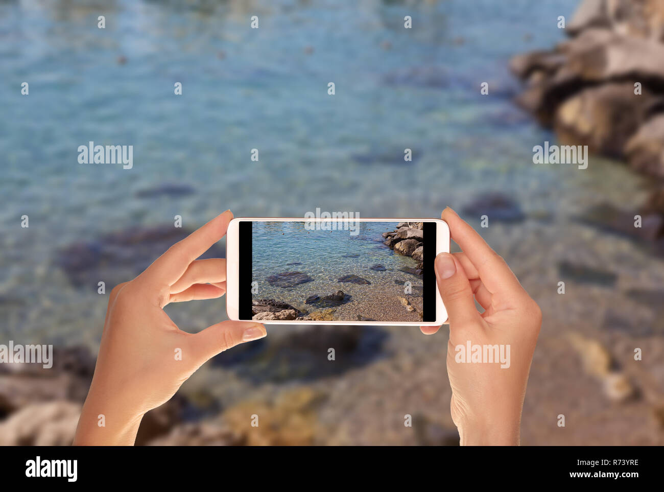 Un turista è di scattare una foto di una piccola parte di spiaggia di ciottoli con acqua chiara sulla Costiera Amalfitana su un telefono cellulare Foto Stock