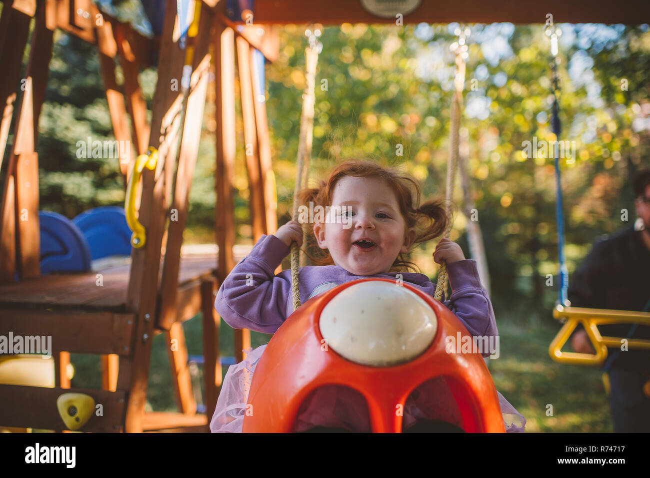 La ragazza con i capelli rossi basculante in parco giochi altalena, ritratto Foto Stock