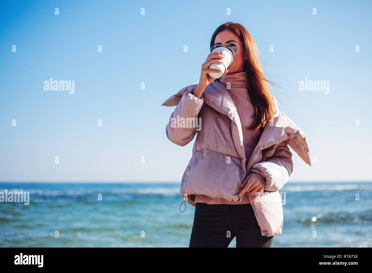 Elegante metà donna adulta sulla spiaggia a bere il caffè da asporto, Odessa, Odeska, Oblast di Ucraina Foto Stock