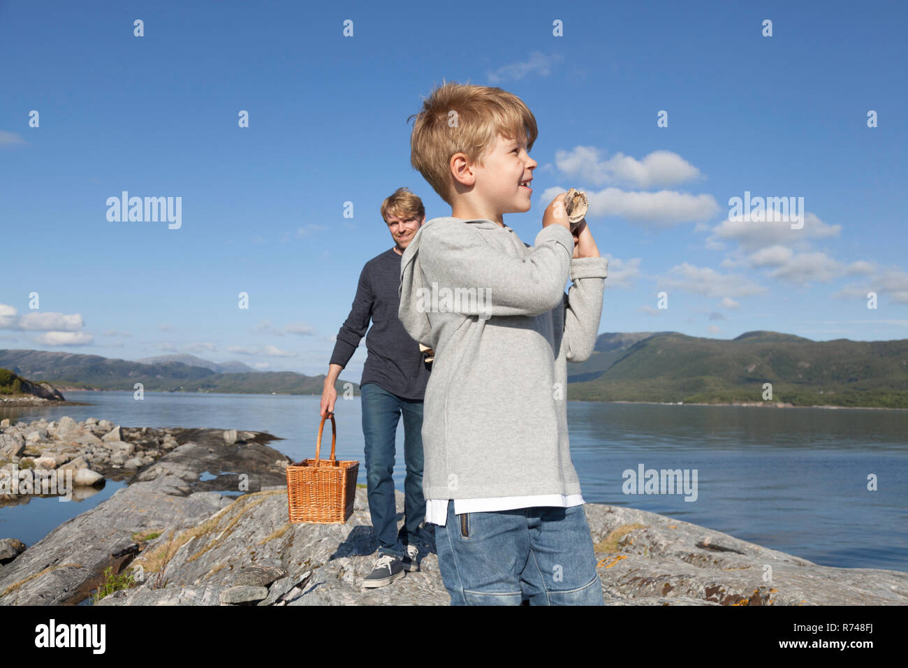 Ragazzo e del padre che porta cestello sulla roccia di ingresso, Aure, More og Romsdal, Norvegia Foto Stock