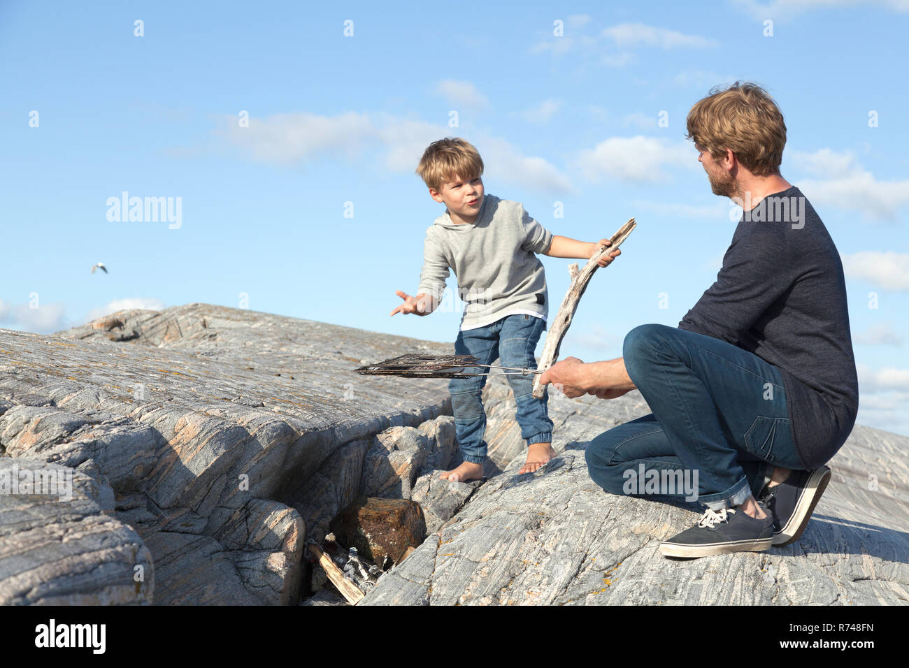 Ragazzo e padre preparazione falò sulla roccia di ingresso, Aure, More og Romsdal, Norvegia Foto Stock