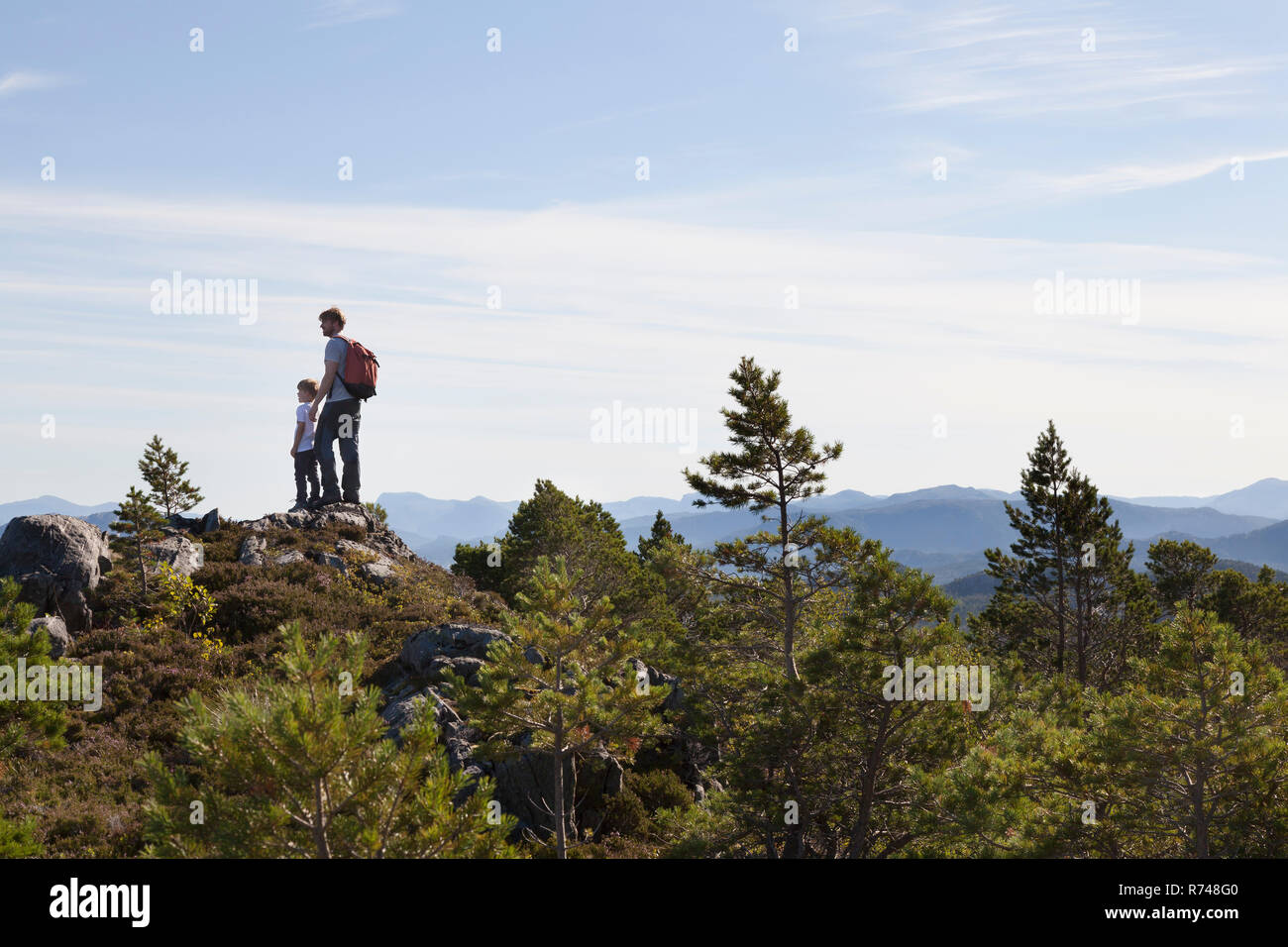 Ragazzo e padre guardando fuori da Woodland Hill oltre il paesaggio, Aure, More og Romsdal, Norvegia Foto Stock