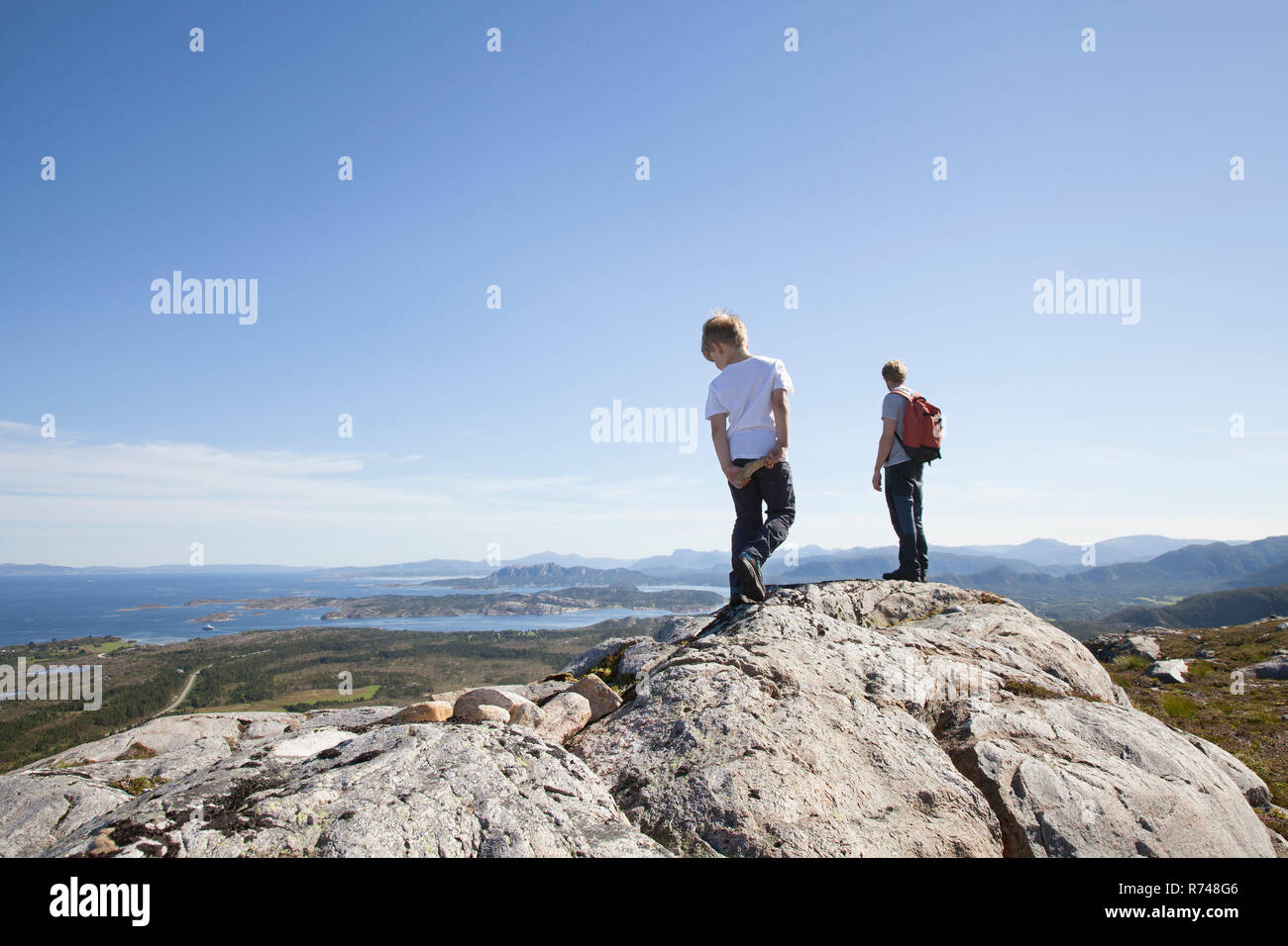 Ragazzo e padre guardando fuori dalla formazione di roccia oltre il paesaggio, Aure, More og Romsdal, Norvegia Foto Stock