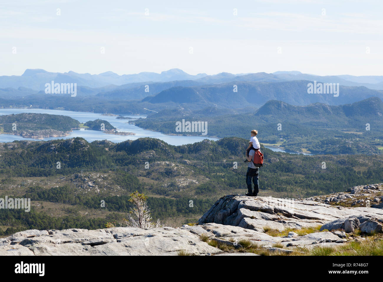 Ragazzo e padre guardando fuori all'ingresso paesaggio dalla formazione di roccia, Aure, More og Romsdal, Norvegia Foto Stock