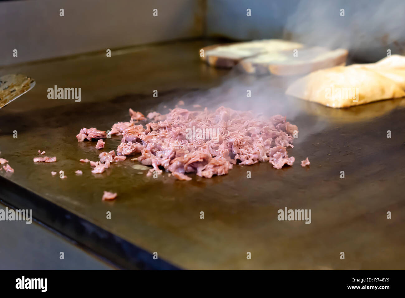 La realizzazione di un sandwich di Ruben. " Corned beef " in un ristorante flat top grill. Il vapore in aumento. In marmo pane di segale la tostatura in background. Foto Stock