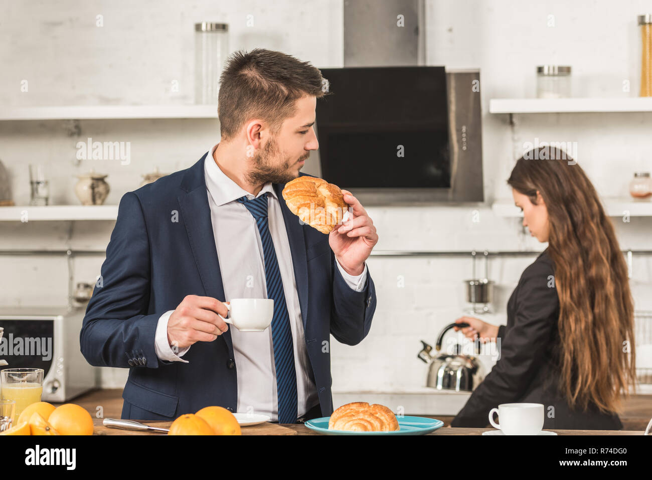 Ragazzo con colazione e ragazza mettendo il bollitore sulla stufa a casa, gli stereotipi di genere nozione Foto Stock