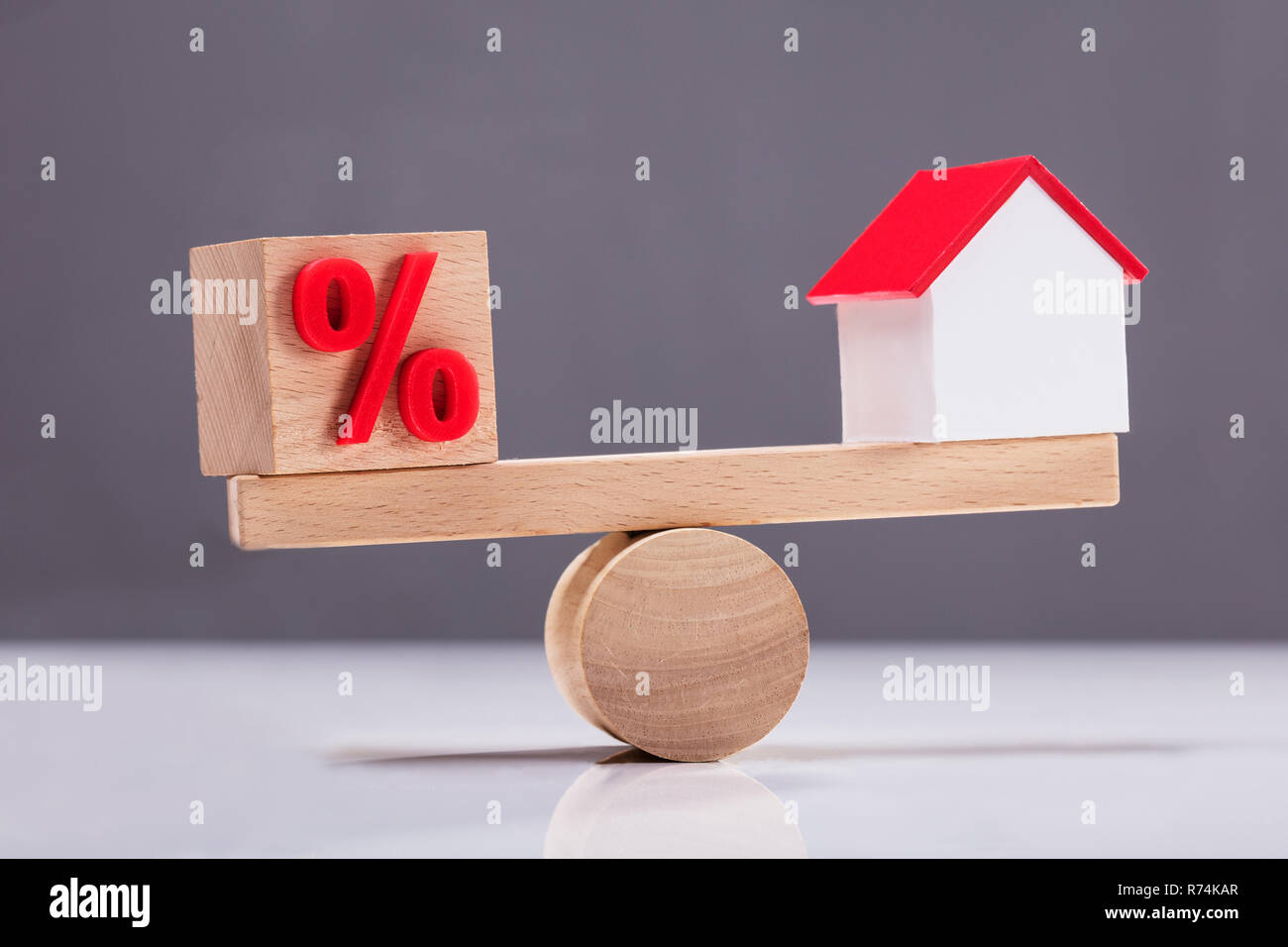 Altalena che mostra l'equilibrio tra il simbolo di percentuale e modello di casa Foto Stock