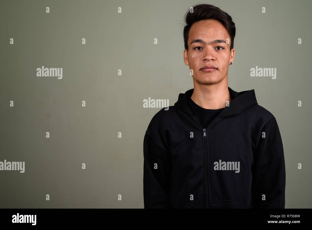 Bel giovane uomo indiano indossando hoodie contro backgro colorati Foto Stock