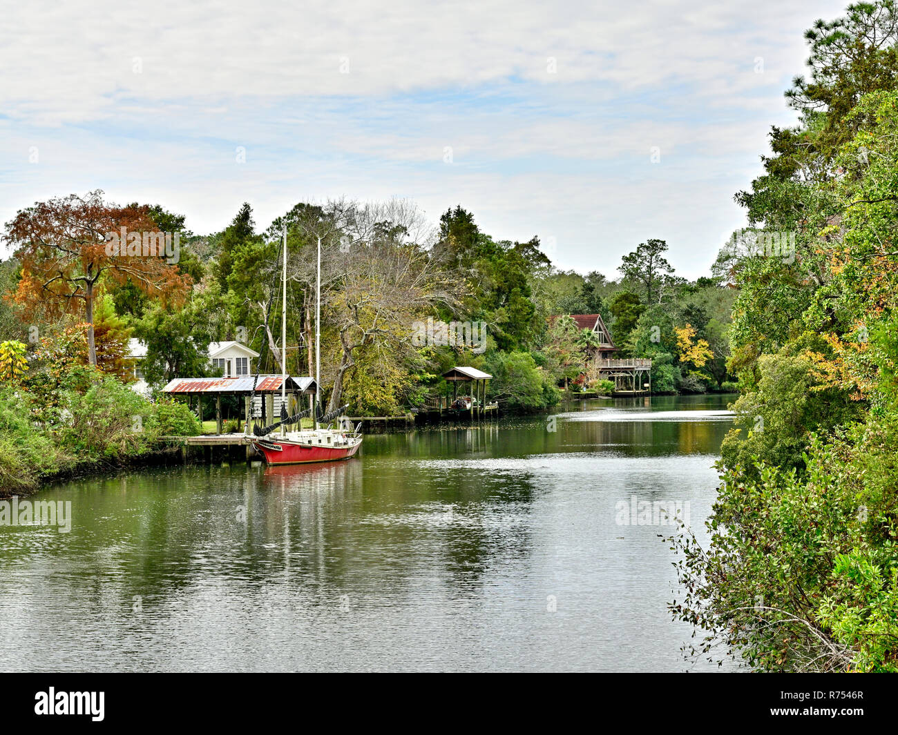 Rosso unica barca a vela legata a un piccolo molo sul Eslava succursale o il Bayou in South Alabama, Stati Uniti d'America. Foto Stock