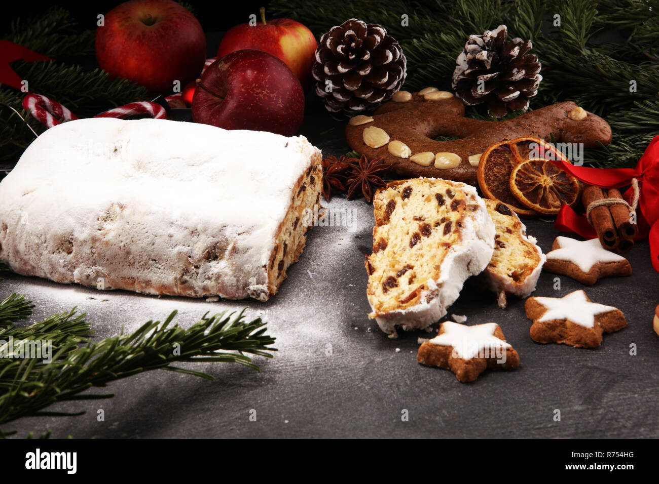 Europeo tradizionale pasticceria di Natale, fragrante cotto domestico stollen con spezie e frutta secca. Affettare sul tavolo rustico con il natale a rami di alberi e de Foto Stock