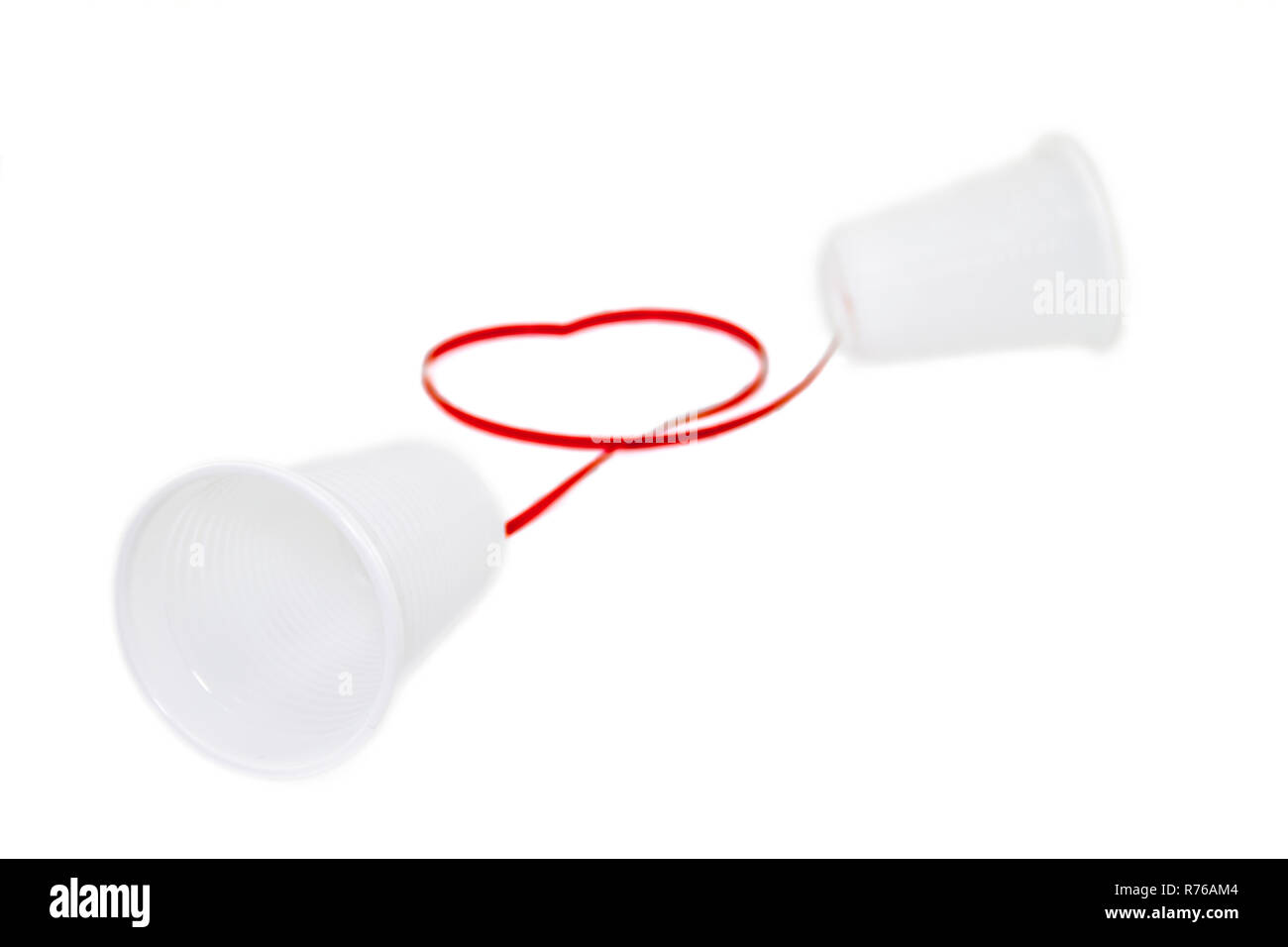 Lunga distanza concetto di relazione. Bianco 2 tazze di plastica collegato con un filo rosso Foto Stock