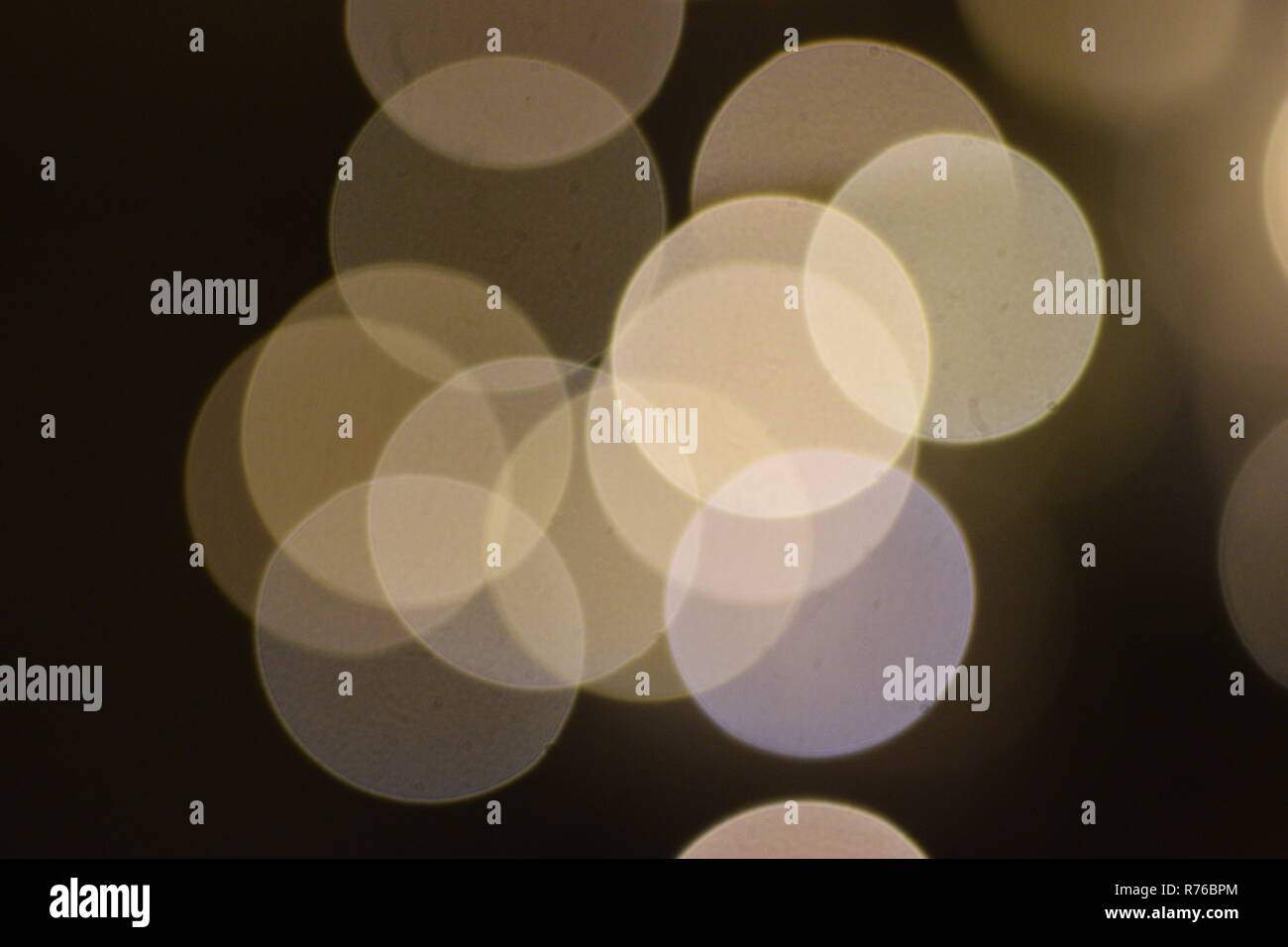 Molti luminosi cerchi sfocate sovrapposizione contro uno sfondo scuro, elemento di design Foto Stock
