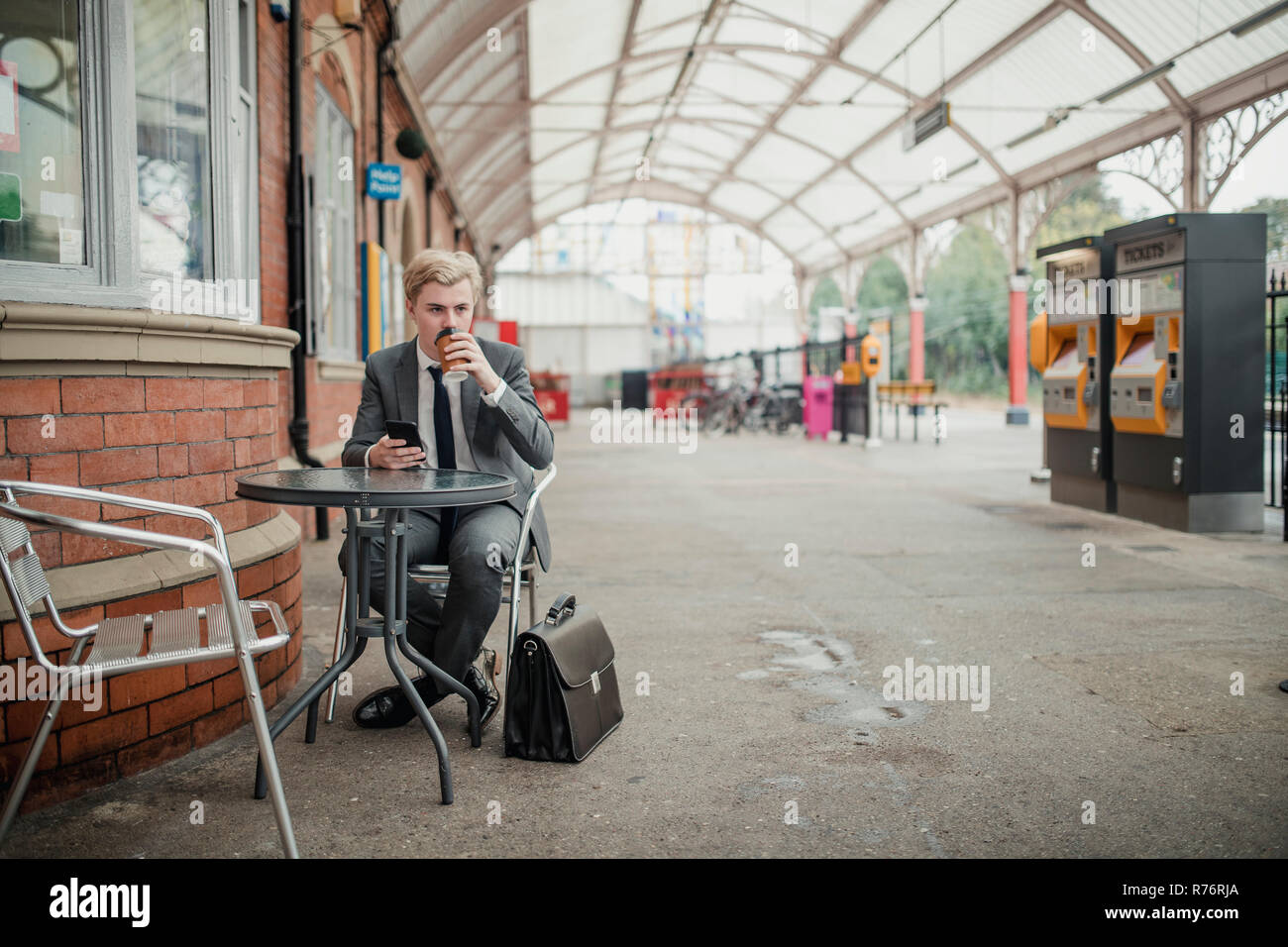 Imprenditore a bere caffè e in attesa di un treno Foto Stock