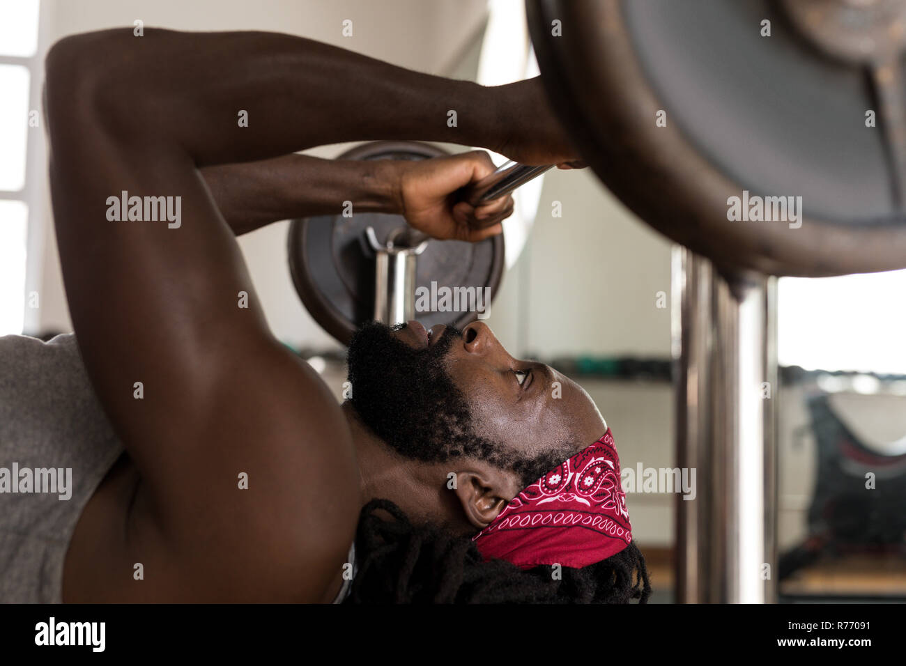 Boxer maschio esercitando con pressa da banco barbell in studio fitness Foto Stock
