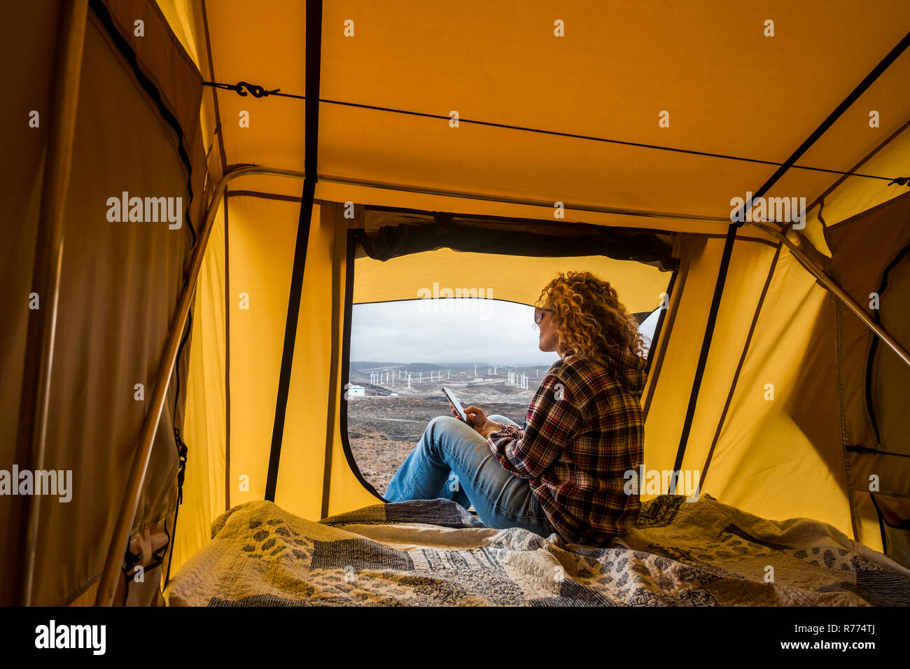 Alternativa libera vacanza donna dentro una tenda guardando il panorama esterno e utilizzare la tecnologia internet telefono cellulare collegato a rimanere collegato wit Foto Stock