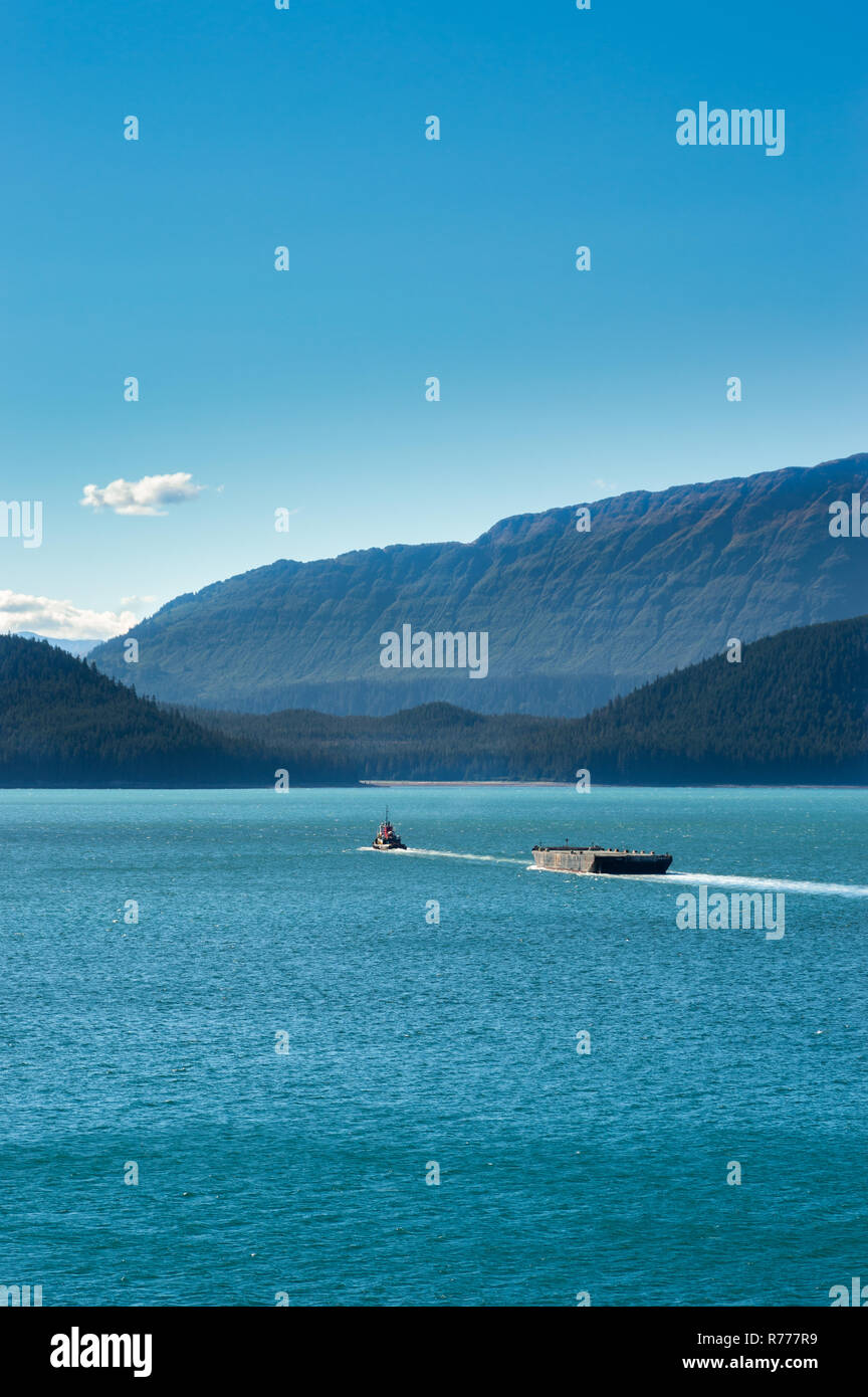 Rimorchiatore tirando includersi in una giornata di sole nel canale Gastineau, vicino a Juneau, Alaska, Stati Uniti d'America. Isola di Douglas in background. Foto Stock