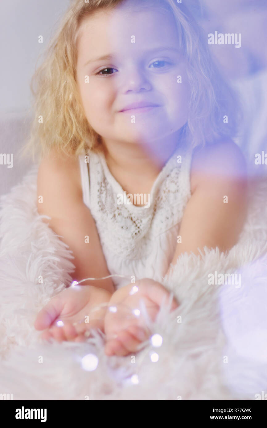 Bellissima bambina incandescente con le luci di Natale; Sfondo Inverno Foto Stock