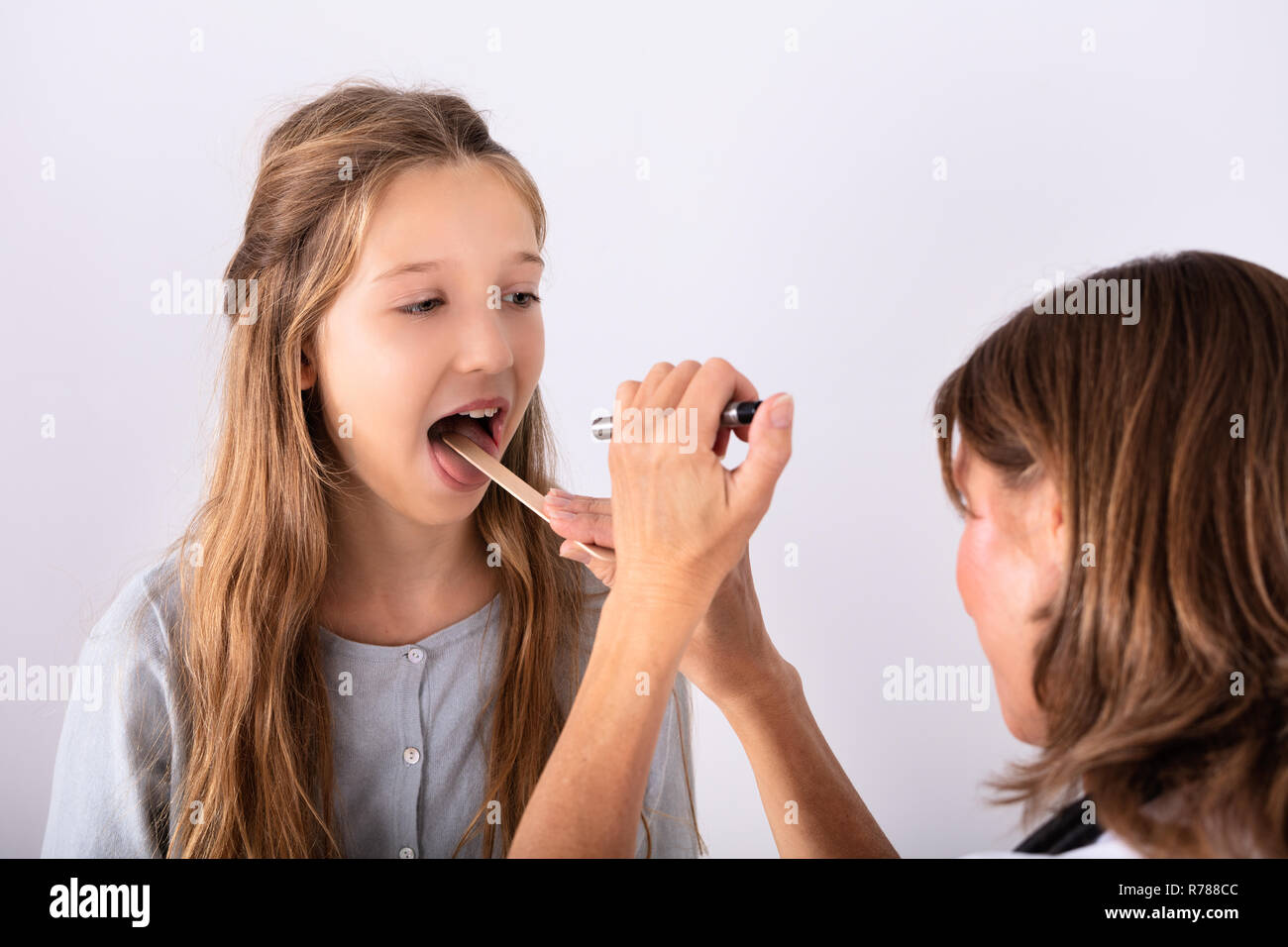 Close-up di controllo medico la ragazza mal di gola con abbassa lingua Foto Stock