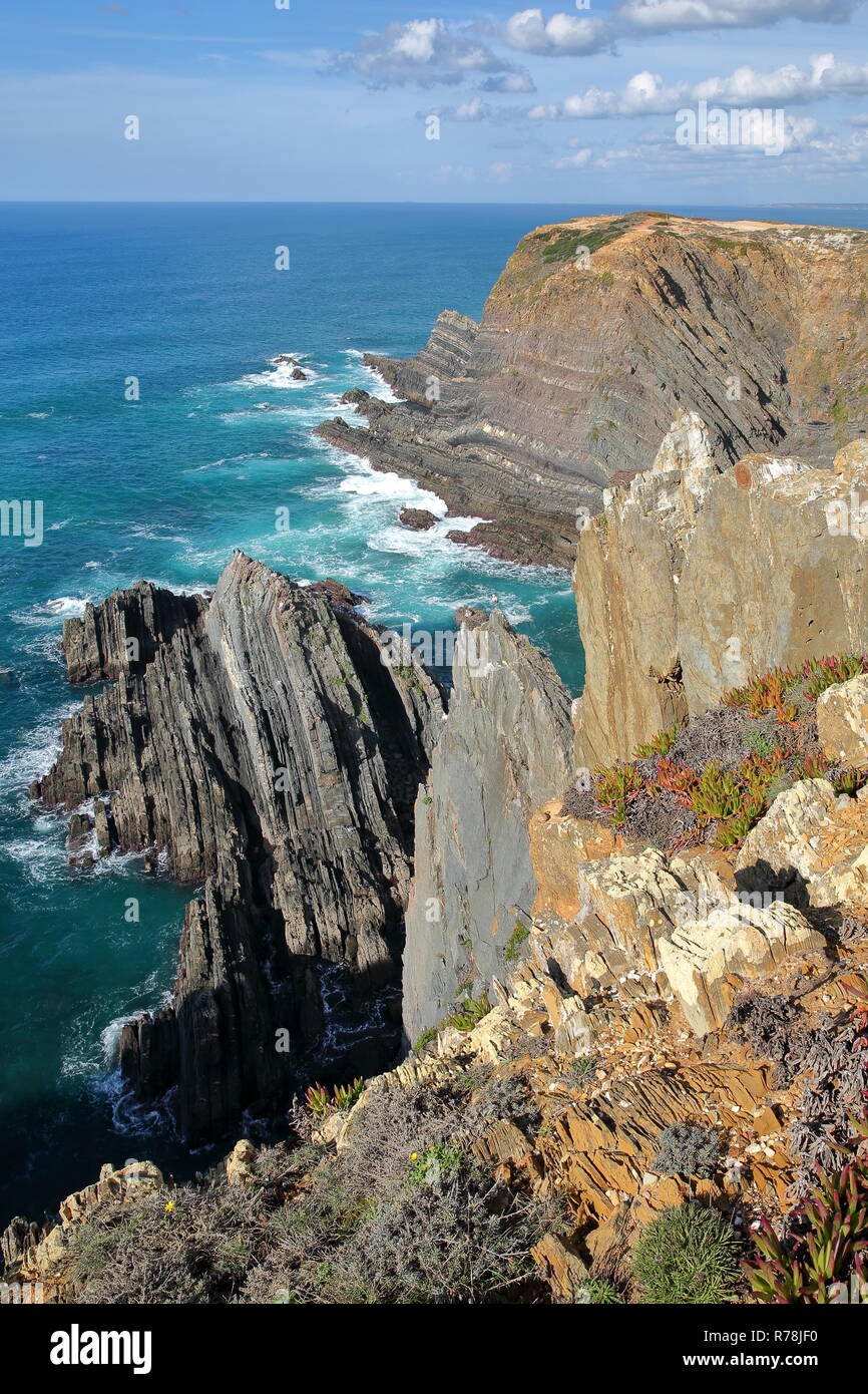 Drammatica e scogli colorati sul Alentejo West Coast a Cabo Sardao, Alentejo, Portogallo, con cicogne bianche nidificanti nella parte superiore delle scogliere rocciose Foto Stock